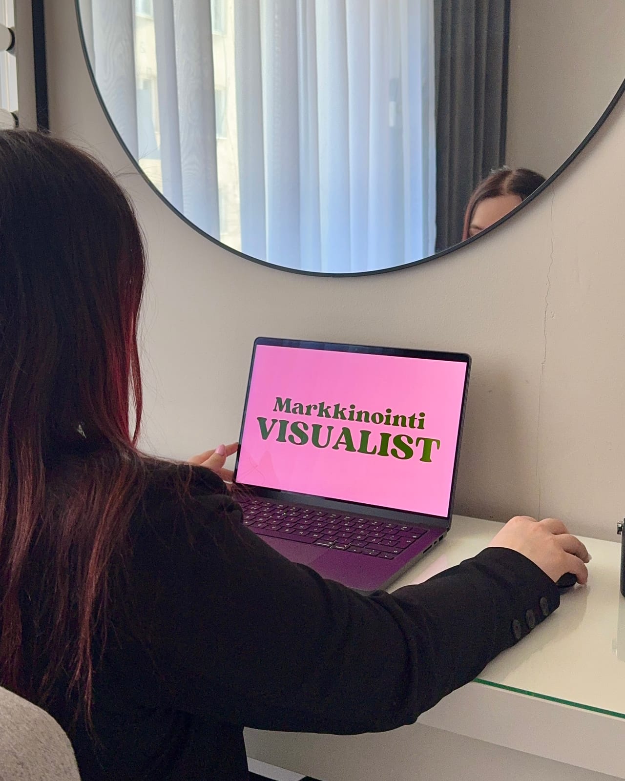 Silja työpisteellään, näkymässä laptopin ruudulla Markkinointi Visualistin tunnus.